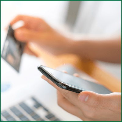Hands holding a credit card using laptop computer and mobile phone for online shopping .