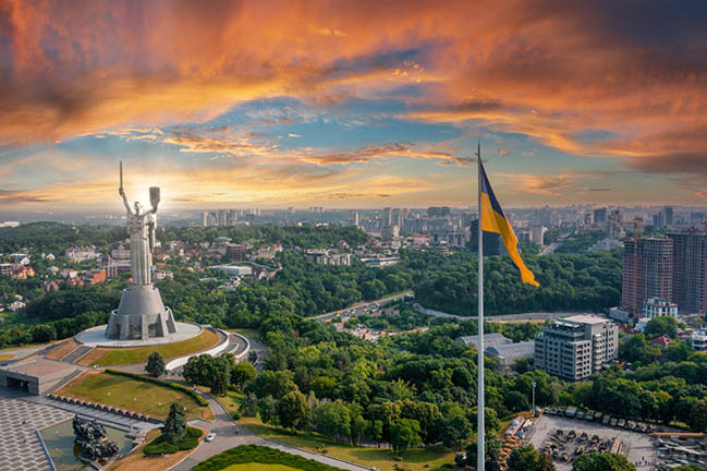 Aerial view of the Ukrainian flag waving in the wind against the city of Kyiv, Ukraine near the famous statue of Motherland.