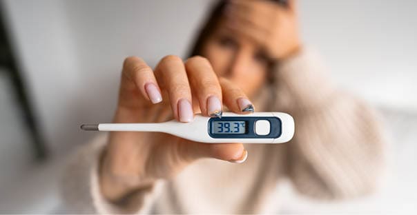 Unhealthy woman with a high fever showing thermometer with high body temperature 39.3. High quality photo